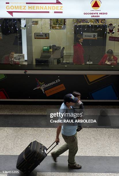 Man walks with his son past the regional bus ticket counters at the North Bus Terminal in Medellin, Antioquia department, on January 5, 2012 during a...