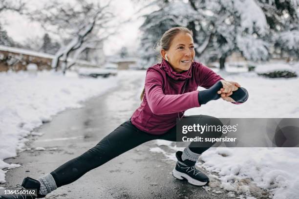 seniorin joggt im freien im schnee - laufen winter stock-fotos und bilder