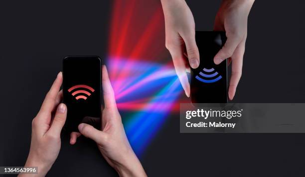 wireless data or money transfer between two smartphones. cryptocurrencies - bluetooth stock-fotos und bilder