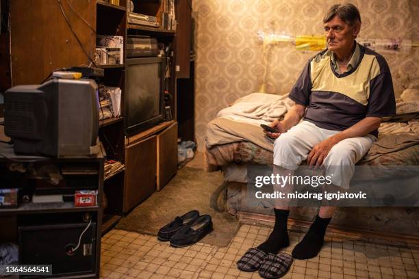 socially vulnerable senior man, from his modest home watching tv - man watching tv alone bildbanksfoton och bilder