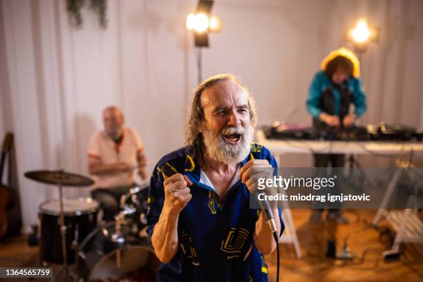 senior singer having a performance with his band - popmuzikant stockfoto's en -beelden
