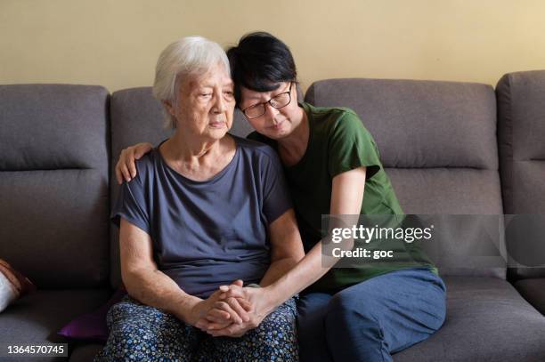 asian daughter spending time with her elderly mother at home - dementie stockfoto's en -beelden