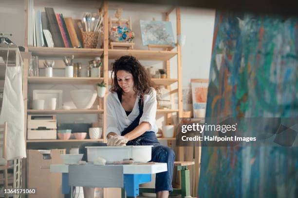 mid adult woman, making pottery on a pottery wheel in art studio. - cerámica fotografías e imágenes de stock