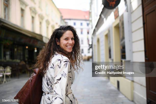 happy young woman turning while walking in town in summer. - slovakia town stock pictures, royalty-free photos & images