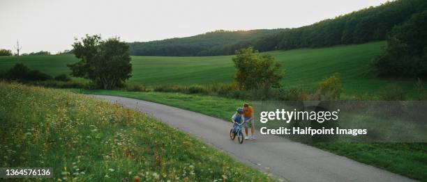 father teaching his little son to ride a bicycle outdoors in nature. - 遠距離拍攝 個照片及圖片檔