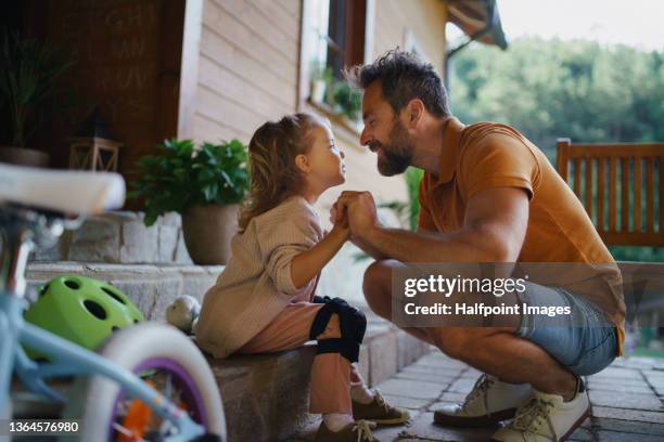 mature man preparing his daughter for first bike ride outdoors in front yard. - protective sportswear stock pictures, royalty-free photos & images
