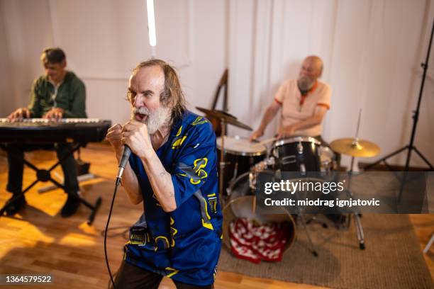 passionate senior male singer, singing during perforance with his band - rap band stock pictures, royalty-free photos & images