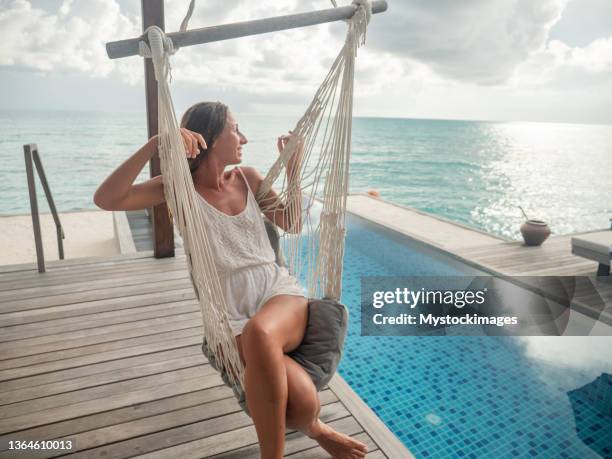 junge frau entspannt sich im luxushotel auf den malediven - strand hängematte stock-fotos und bilder