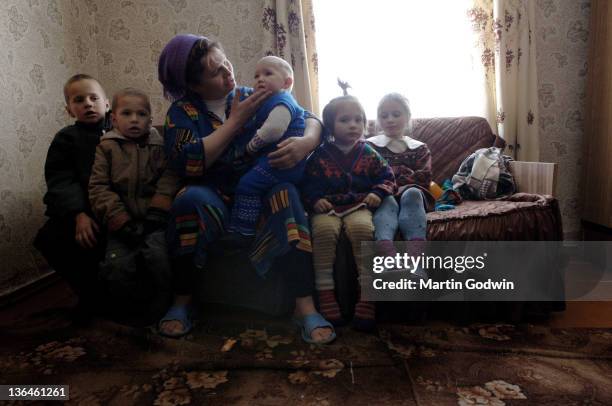 Valentina Molchanovich, wearing a head scarf and her five children on a settee in her house, in the village of Budimlya, near the town of Sarny, near...