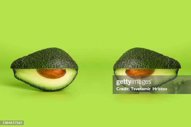 fresh cut avocado shaped like eyes isolated on green background. creative surreal food concept. - green salad stock pictures, royalty-free photos & images