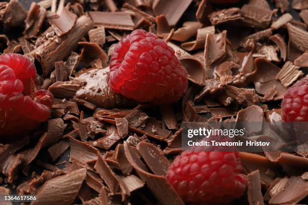 close-up of chocolate shavings near cocoa beans with fresh raspberries. - chocolate chunk stock-fotos und bilder