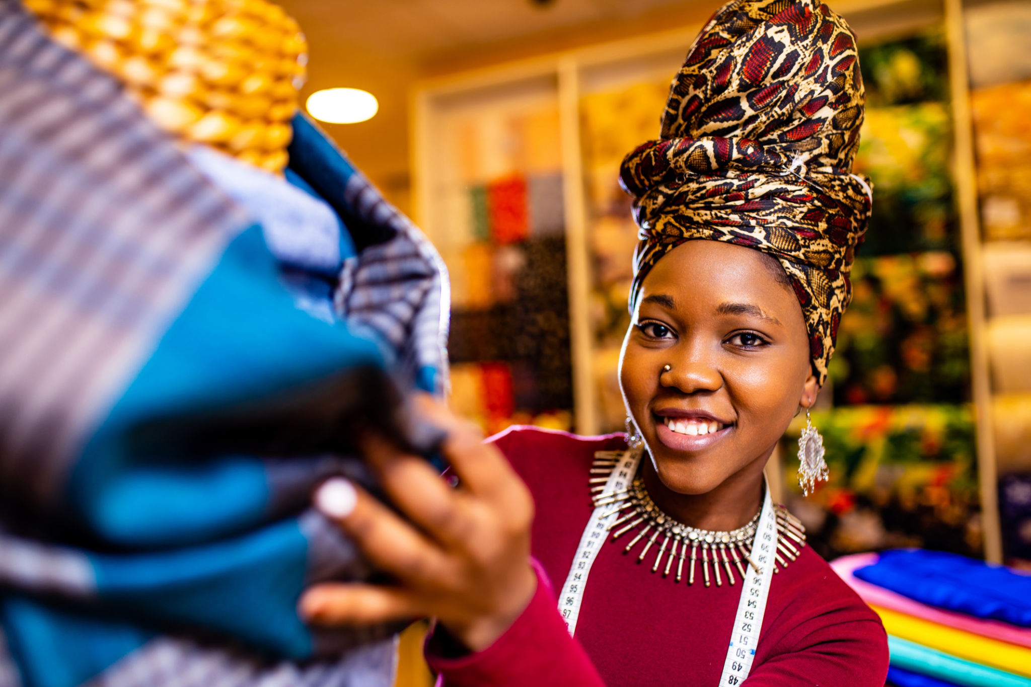 tanzanian woman with snake print turban over hear working in fabrics shop tanzanian woman with snake print turban over hear working in fabrics shop