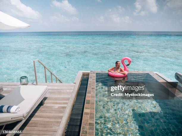 woman enjoying luxury vacations in an overwater bungalow - plastic flamingo stock pictures, royalty-free photos & images