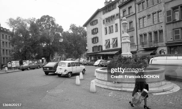 Femme devant une fontaine avec un sac de course à Genève en octobre 1975.