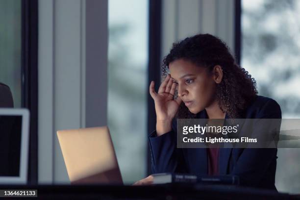 Stressed woman looks at laptop in office