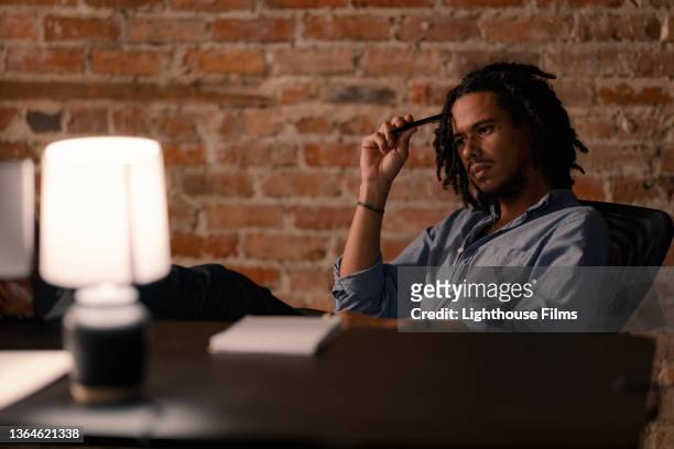 man working late stresses at his desk - desk lamp fotografías e imágenes de stock