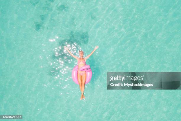 drohnenansicht der frau, die auf aufblasbarem flamingo schwebt - luftmatratze von oben stock-fotos und bilder