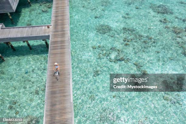 drone view of woman riding bicycle on wooden pier in the maldives - cycling drone bildbanksfoton och bilder