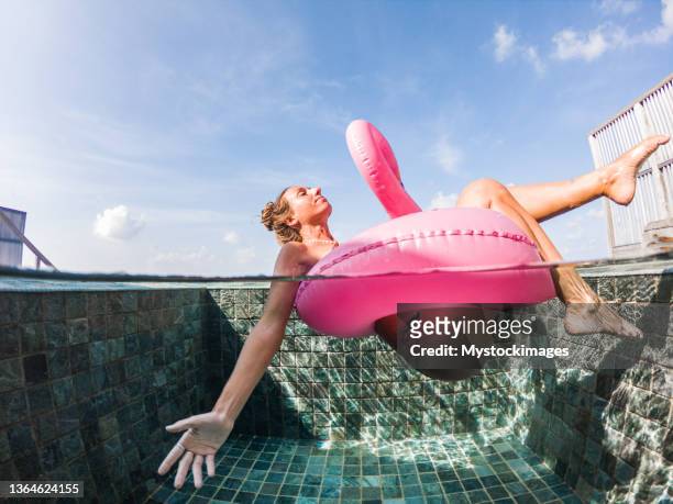 woman plays with inflatable flamingo in swimming pool - half full 個照片及圖片檔