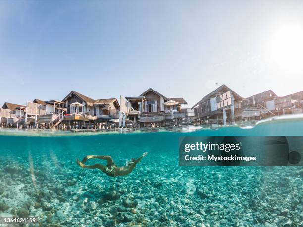 man dives in tropical sea, split screen underwater shot, overwater villas on background - máscara de mergulho imagens e fotografias de stock