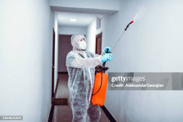 hallway sanitizing by male medical expert in protective suit - white suit stock pictures, royalty-free photos & images