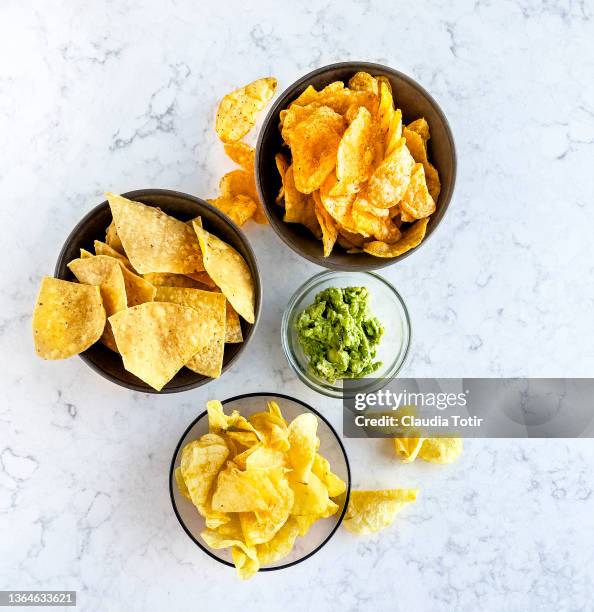 variety of chips in bowls on white, marble background - crisps stockfoto's en -beelden