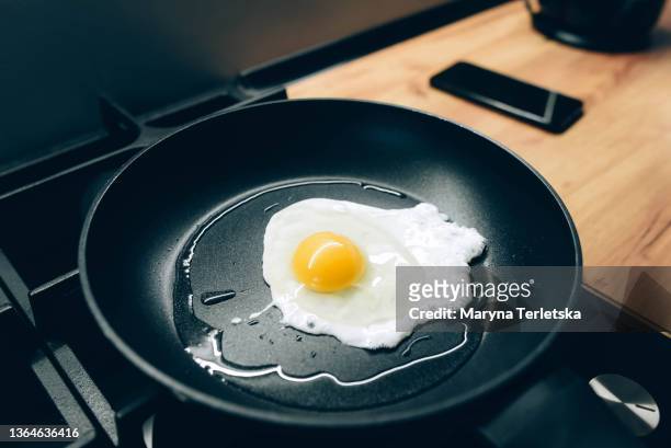 fried eggs are fried in a black skillet. fried eggs. modern cuisine. non-stick frying pan. - cooking pan stock pictures, royalty-free photos & images