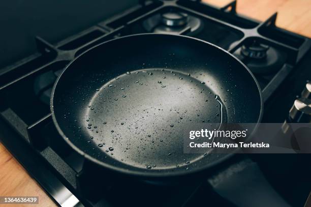 a clean frying pan with water droplets is on the stove. modern cuisine. cooking. frying pan. - frigideira panela - fotografias e filmes do acervo