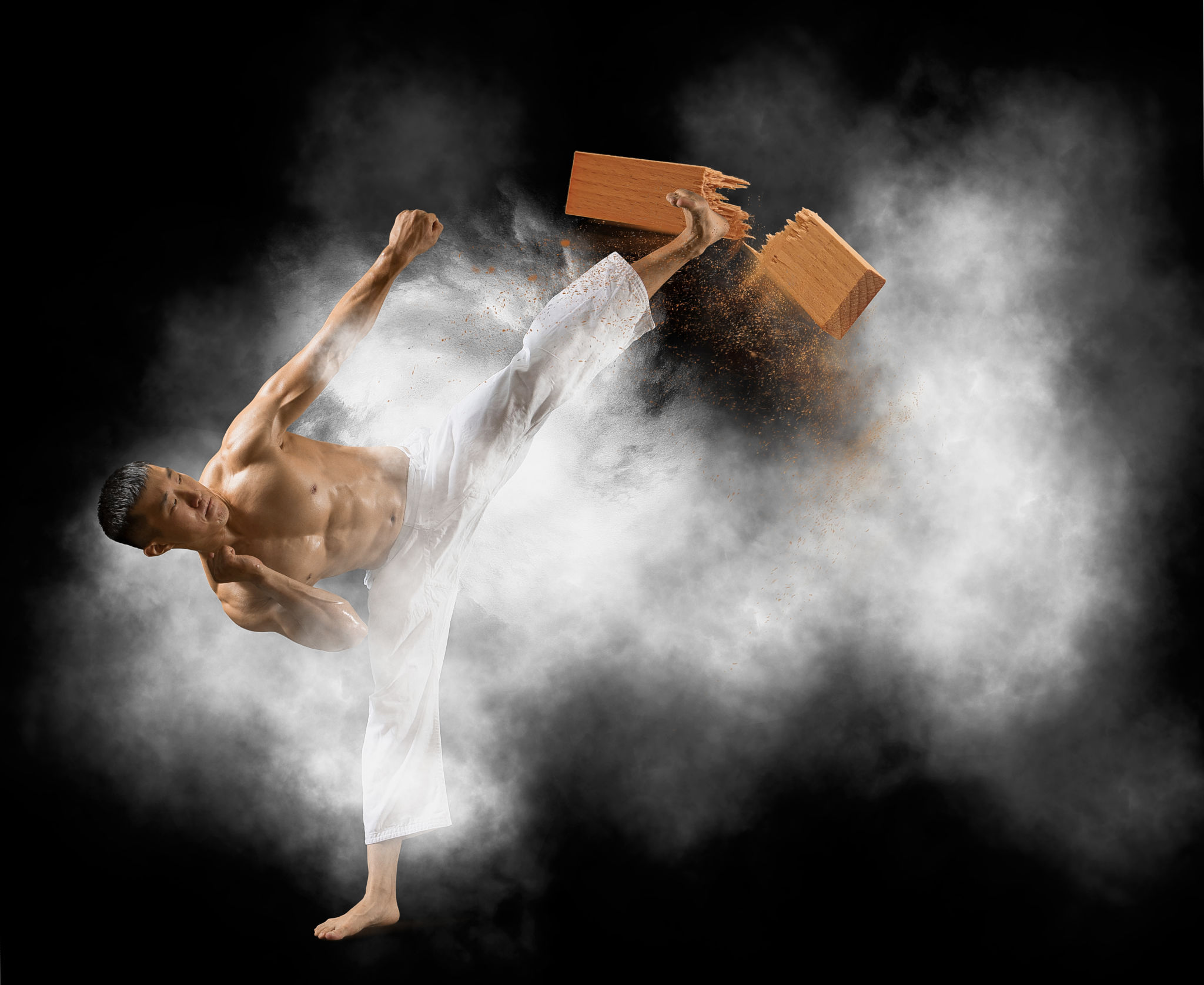 Karate man breaking with leg wooden board Karate man breaking with leg wooden board