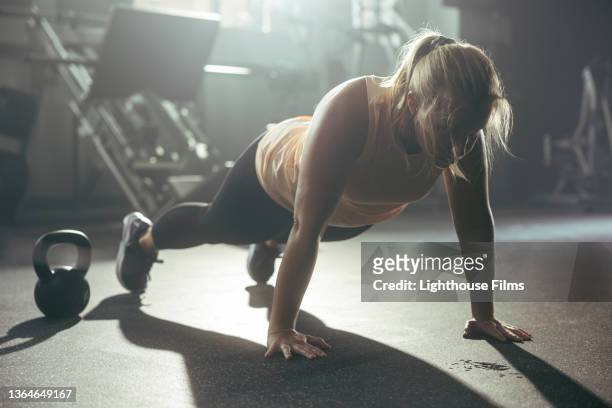 woman does push ups in a gym - press ups stockfoto's en -beelden