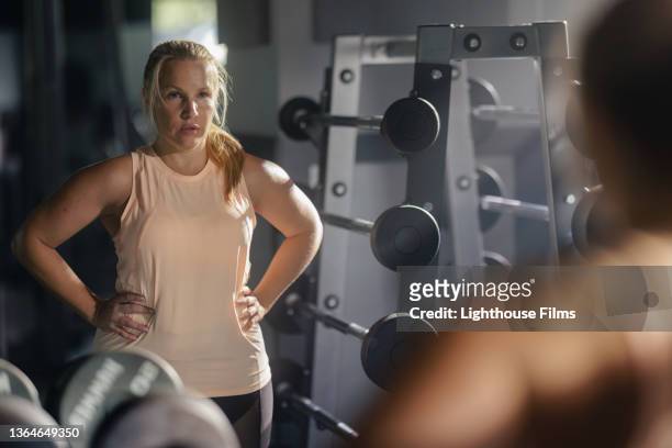 woman looks at reflection in gym mirror - real body fotografías e imágenes de stock