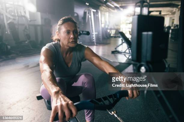 woman uses rowing machine in the morning - gym equipment stock-fotos und bilder