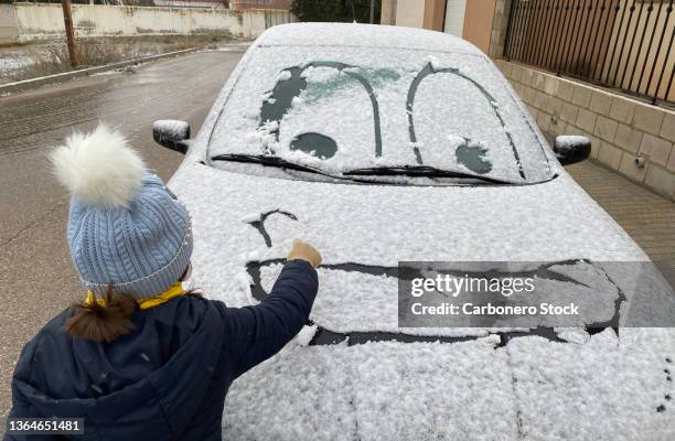 little girl drawing a face on the snowy car window - funny pics of people photos et images de collection