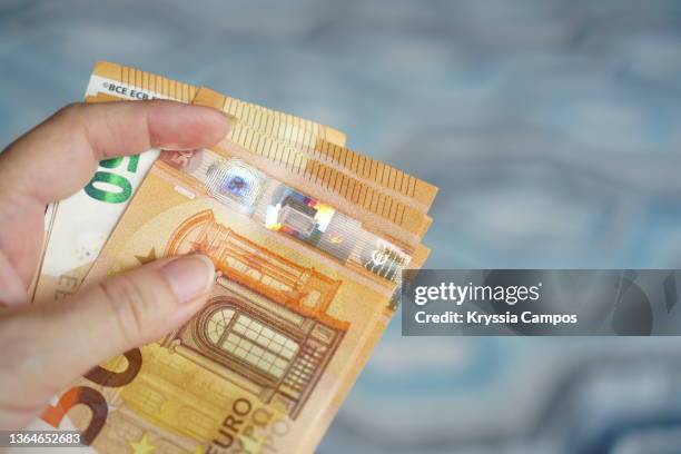 hand holding out money, euro paper currency - billet de 50 euros photos et images de collection