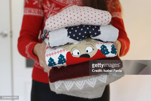 close-up of woman hands holding stack of warm sweaters - suéter natalino - fotografias e filmes do acervo