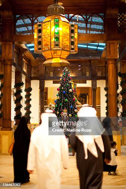 Qatari people in their traditional clothes called dishdasha and abaya look at a christmas tree inside the still under construction man-made peninsula...