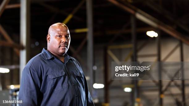 african-american man working in dark warehouse - testosterone stockfoto's en -beelden