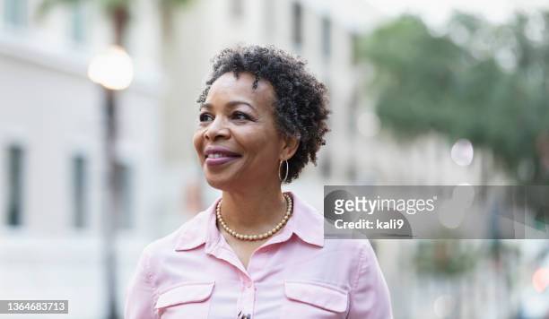 headshot of mature black woman walking on city street - city life authentic stockfoto's en -beelden