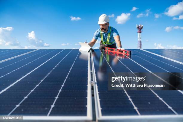 low angle view of male technicians working on solar panels against sky - técnica de fotografia imagens e fotografias de stock