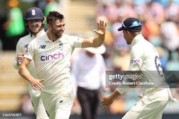 Mark Wood of England celebrates his wicket of Pat Cummins of Australia with Joe Root during day two of the Fifth Test in the Ashes series between...