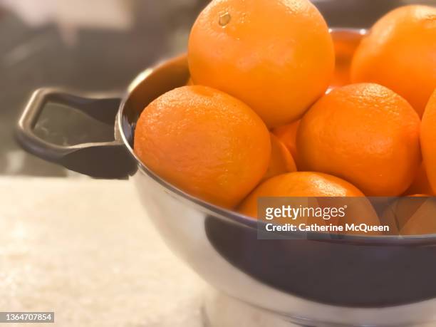 stainless steel colander brimming with fresh oranges - navel orange stock pictures, royalty-free photos & images