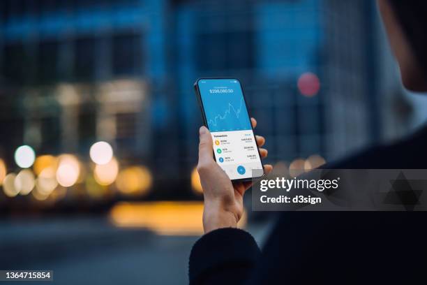 over the shoulder view of asian woman using nft investment wallet on smartphone in city street, working with blockchain technologies, investing or trading nft (non-fungible token) on cryptocurrency, digital asset, art work and digital ledger - augmented reality phone stock-fotos und bilder