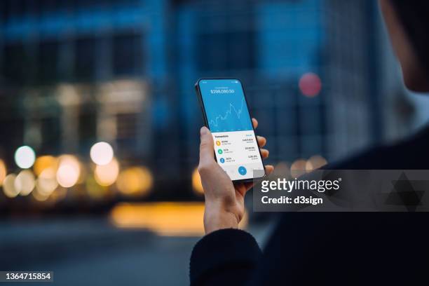 over the shoulder view of asian woman using nft investment wallet on smartphone in city street, working with blockchain technologies, investing or trading nft (non-fungible token) on cryptocurrency, digital asset, art work and digital ledger - non urban scene stockfoto's en -beelden
