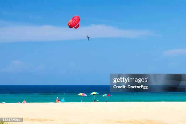 scenic view of andaman sea with red parasailing background in summer at karon beach, phuket - parasailing stock pictures, royalty-free photos & images
