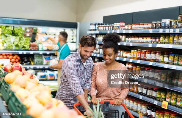 multiracial family buying groceries in supermarket, choosing fresh fruit - consumer confidence stock pictures, royalty-free photos & images