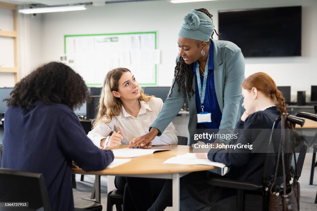 Alumnas trabajando en la tarea con la ayuda del maestro