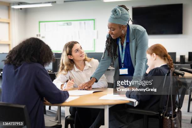 female students working on assignment with help from teacher - teacher stock pictures, royalty-free photos & images