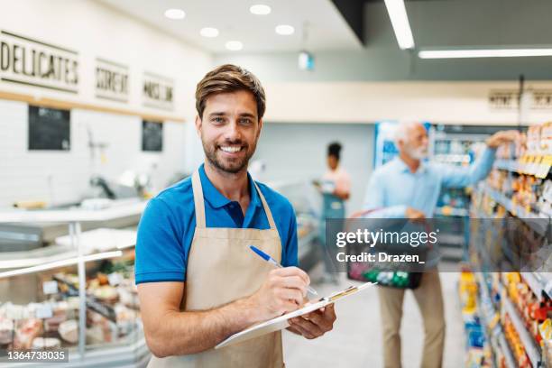 empleado en el supermercado, gerente de la tienda que llena pedidos y sonríe mientras mira a la cámara - friendly salesman fotografías e imágenes de stock