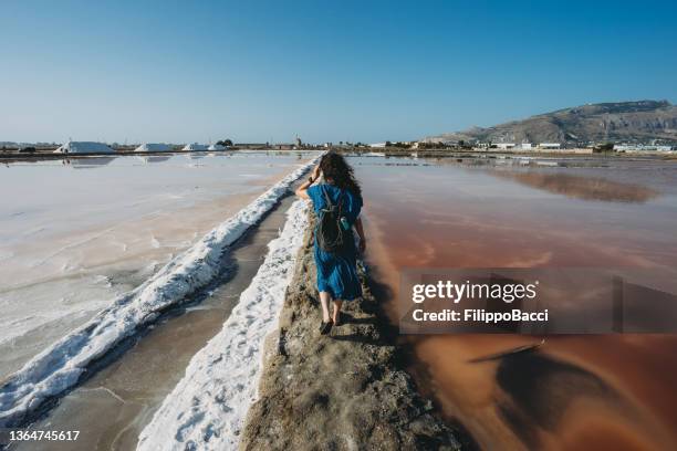 a woman is standing in the middle of orange salt flats in sicily, italy - marsala stock pictures, royalty-free photos & images