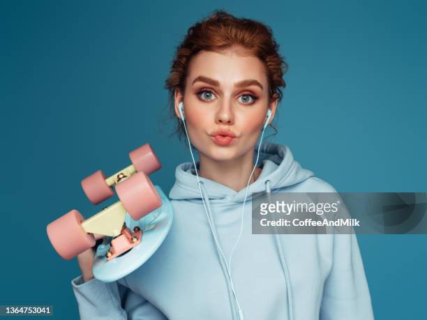 close-up portrait of a young pretty girl in a blue hoodie using smart phone - beauty portrait studio shot stockfoto's en -beelden
